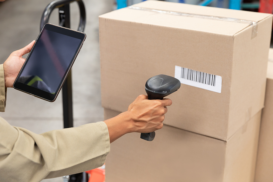 Close-up of female worker scanning package with barcode scanner in a warehouse